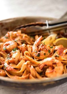 a bowl full of pasta with shrimp and sauce