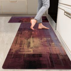 a person standing on top of a rug in a kitchen next to an oven and cabinets