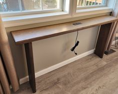 a long wooden table sitting next to a window on top of a hard wood floor