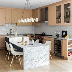 a modern kitchen with marble counter tops and wooden cabinets, along with an island in the middle