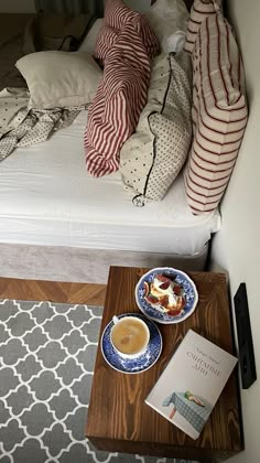 a bed with two pillows and a bowl of food on the end table next to it