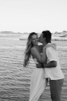 black and white photograph of a couple kissing on the beach in front of the ocean