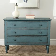 a blue dresser with two books on top and a white vase sitting on the bottom