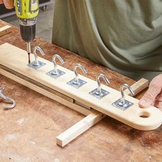 a person using a drill to attach hooks on a piece of wood