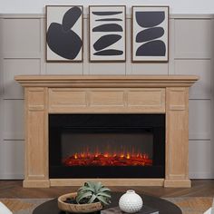 a living room with a fire place and two pictures on the wall above it's fireplace