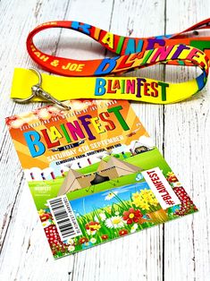 two lanyards are sitting next to each other on a white wooden surface, one has a name tag and the other has a colorful lanyard