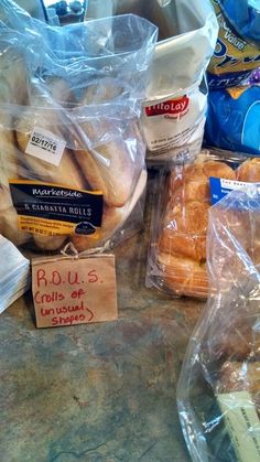 breads and other food items are on the counter in front of some plastic bags