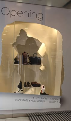 a display case with shoes and handbags in it's glass front window that says, opening