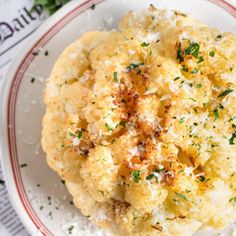 cauliflower with parmesan cheese and herbs on top in a red and white plate