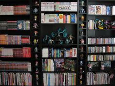 a book shelf filled with lots of books and video game controllers on top of it