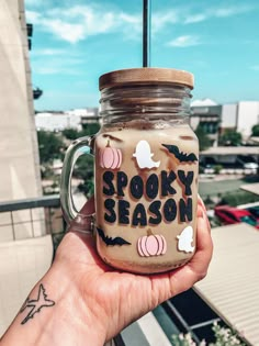 a person holding a mason jar with spooky season written on it