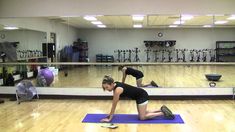 a woman is doing yoga on a mat in the middle of a room with mirrors