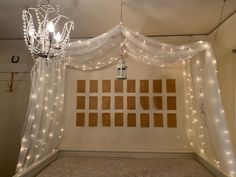 a bed with white curtains and lights hanging from the ceiling