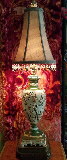 a lamp sitting on top of a wooden table next to a red and gold wall