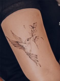 a woman's thigh with a hummingbird and flower tattoo on the side of her leg