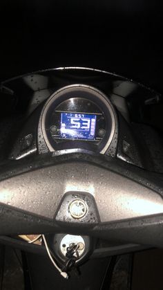 the speedometer is displayed on the dashboard of a motorcycle in the dark, with water droplets all over it