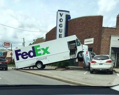 a fed ex truck that has been flipped over in the middle of a street with other cars parked nearby