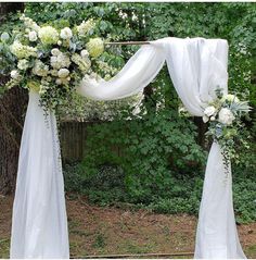 an outdoor wedding arch decorated with white flowers and greenery