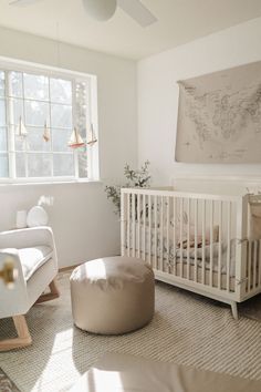 a baby's room with a white crib, rocking chair and large window