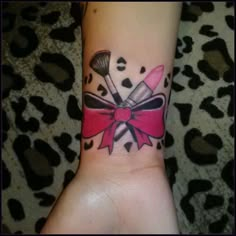 a woman's wrist with a pink bow and two makeup brushes on it