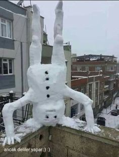 a snowman on top of a building with his arms and legs in the air