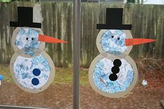 two snowmen made out of paper plates on a window sill