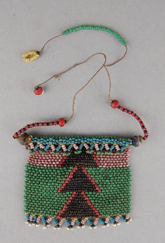 a beaded purse hanging from a string on a white surface with beads around it