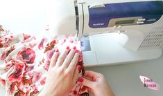 a woman is using a sewing machine to sew flowers on a pink and white blanket