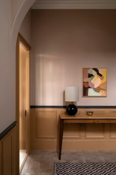 a painting on the wall above a table in a room with wood paneling and beige walls