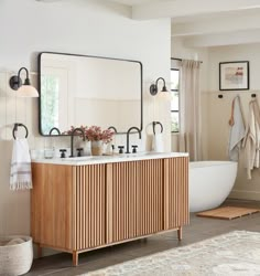 a bathroom with a sink, mirror and bathtub in the corner next to a rug