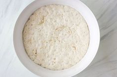 a white bowl filled with dough on top of a table