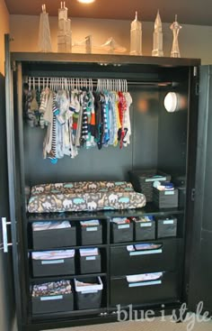 an image of a closet with clothes hanging on the rack and other items in bins