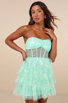 The Lulus Illustrious Glow Mint Green Sheer Tulle Sequin Tiered Mini Dress is perfect for any occasion that calls for extra extravagance! This sensational dress features a sparkling sequin design across the tulle-mesh construction that shapes a strapless, bustier-inspired bodice with sheer mesh paneling (along with supportive boning), a gathered bust with padded cups, and a sweetheart neckline with hidden no-slip strips. The high, fitted waist sits atop a fun and frilly tiered skirt that finishe Cute Dance Dresses, Rapunzel Wedding Theme, Sheer Bustier, Rapunzel Wedding, Green Sequin Dress, Sheer Clothing, Tulle Homecoming Dress, Tier Dress, Strapless Bustier