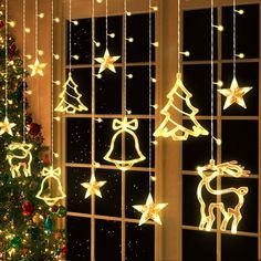 a christmas tree in front of a window decorated with lights