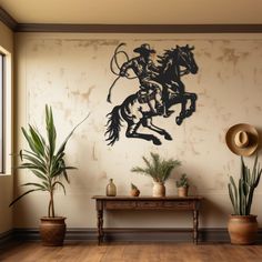 a cowboy riding a horse on the wall next to potted plants and a table