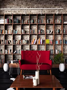 a red couch sitting in front of a book shelf filled with books