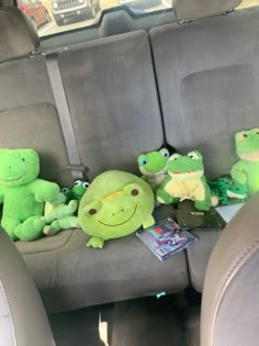 several stuffed animals are sitting in the back seat of a car, including frogs and toades