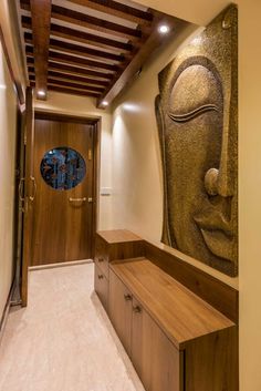 an entry way with a large buddha statue on the wall and a wooden bench in front of it