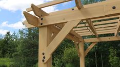 a wooden pergola in front of some trees