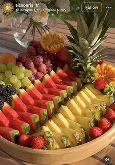 a wooden bowl filled with lots of different types of fruit on top of a table