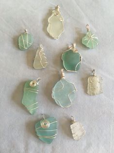 nine different sea glass pendants on a white cloth