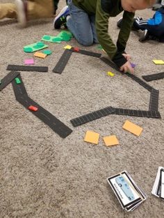 a young boy is playing with some sort of game on the floor while others watch