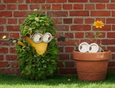 two potted plants with faces on them in front of a brick wall and grass