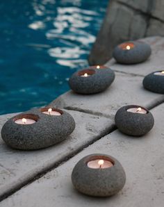 several lit candles are placed on the edge of a pool