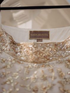 the back of a dress with gold sequins and a name tag on it