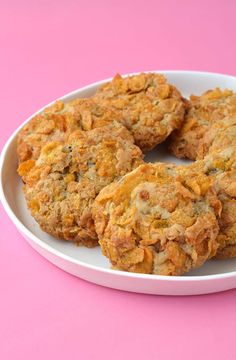 three cookies on a white plate with pink background