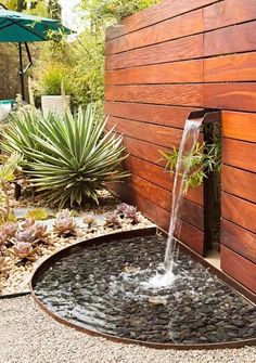 a water fountain in the middle of a garden with succulents and plants