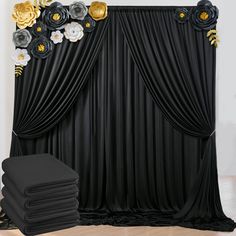 a black backdrop with gold and white flowers on it next to a stack of black chairs