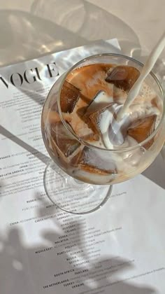 a drink in a glass on top of a table next to a paper with the word voge