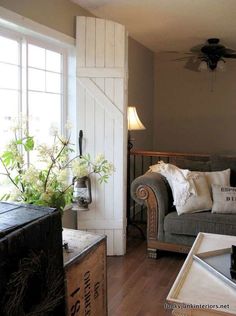 a living room filled with furniture next to a window covered in white flowers and greenery